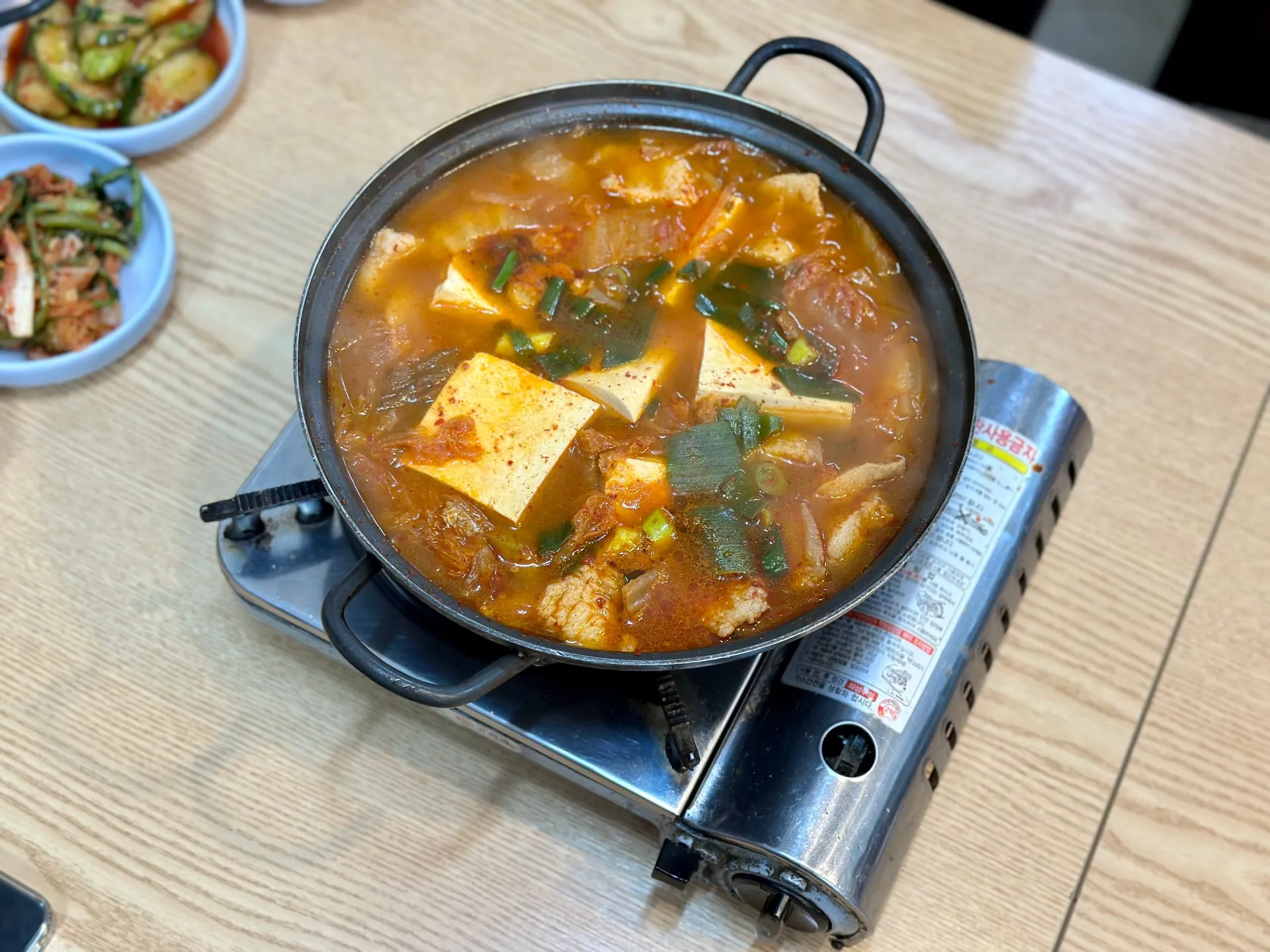 김치찌개 — 직접 담근 한국 김치와 한돈의 만남. 고기는 사장님이 직접 손질해 큼직하게 썰어 넣고 푹 끓여 냅니다.